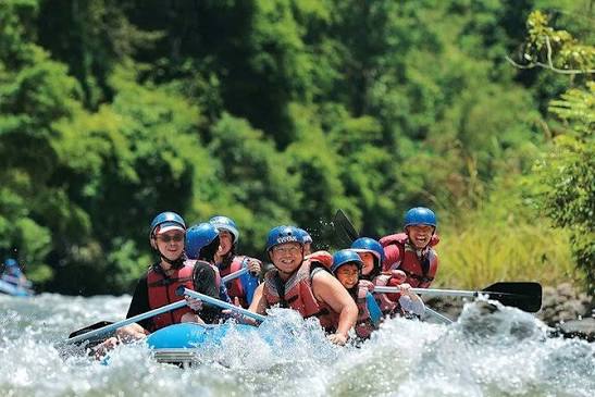 Residents white-water rafting on a Sabah river surrounded by rainforest
